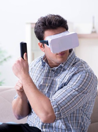 Téléchargez les photos : L'homme qui regarde des lunettes de réalité virtuelle à la maison - en image libre de droit