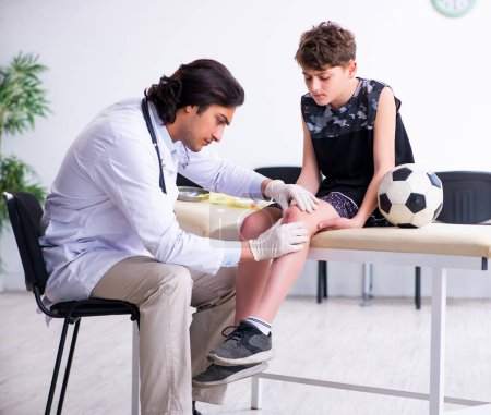Foto de El jugador de fútbol de niño visitando al joven médico traumatólogo - Imagen libre de derechos