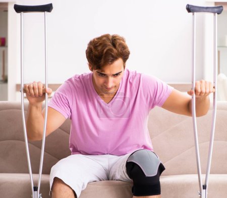 Photo for The young man with injured knee recovering at home - Royalty Free Image