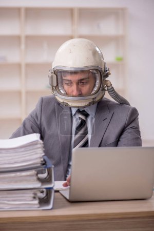 Téléchargez les photos : Young businessman employee wearing spacesuit at workplace - en image libre de droit
