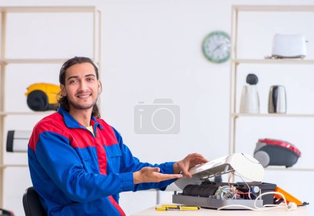 Téléchargez les photos : Le jeune entrepreneur réparer climatiseur à l'atelier - en image libre de droit