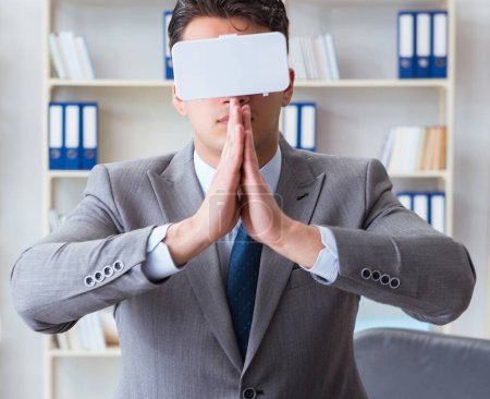 Téléchargez les photos : L'homme d'affaires en réalité virtuelle vr lunettes méditant au sommet du bureau - en image libre de droit