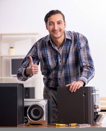 Téléchargez les photos : Le jeune ingénieur répare le système hi-fi musical - en image libre de droit