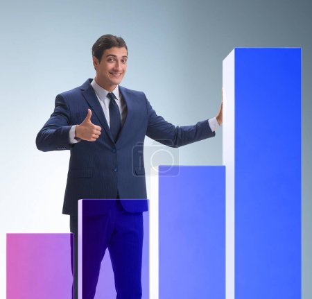 Foto de El hombre de negocios de pie junto a gráfico de barras en concepto de negocio - Imagen libre de derechos