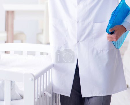 Téléchargez les photos : L'homme pédiatre masculin près du lit de bébé se prépare à examiner - en image libre de droit