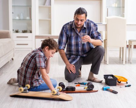 Photo for The young father repairing skateboard with his son at home - Royalty Free Image