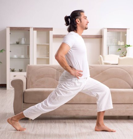 Téléchargez les photos : Le jeune homme faisant des exercices physiques à la maison - en image libre de droit