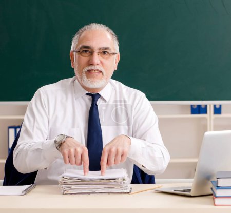 Photo for The aged male teacher in front of chalkboard - Royalty Free Image