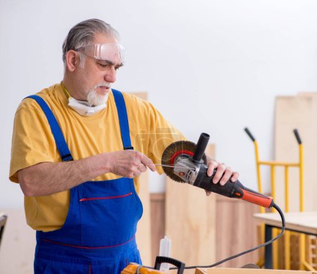 Téléchargez les photos : Le vieil homme charpentier travaillant en atelier - en image libre de droit