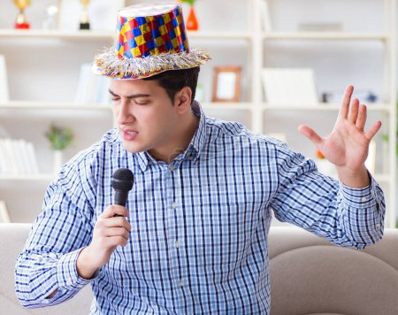 Foto de Hombre divertido cantando canciones en karaoke en casa - Imagen libre de derechos