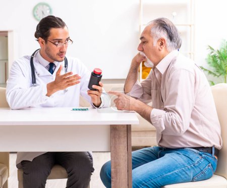 Téléchargez les photos : Le jeune médecin de sexe masculin rend visite à un vieux patient à la maison - en image libre de droit