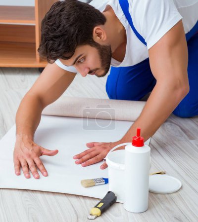 Téléchargez les photos : Réparateur faisant la réparation de rénovation dans la maison avec papier peint - en image libre de droit