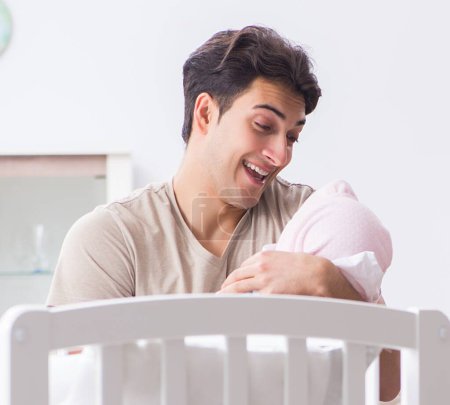 Téléchargez les photos : Jeune père appréciant le temps avec le nouveau-né à la maison - en image libre de droit