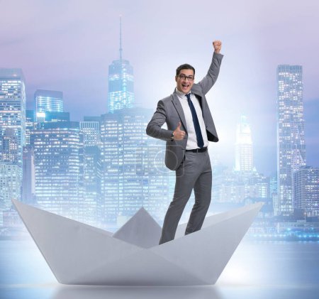 Téléchargez les photos : L'homme d'affaires excité chevauchant bateau de papier - en image libre de droit