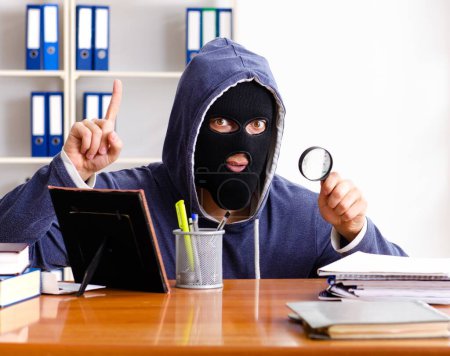 The male thief in balaclava in the office