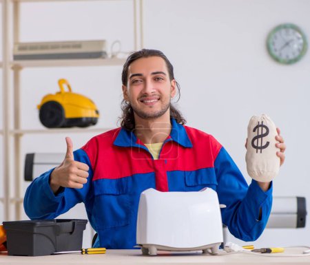 Foto de El joven contratista reparando tostadora en el taller - Imagen libre de derechos