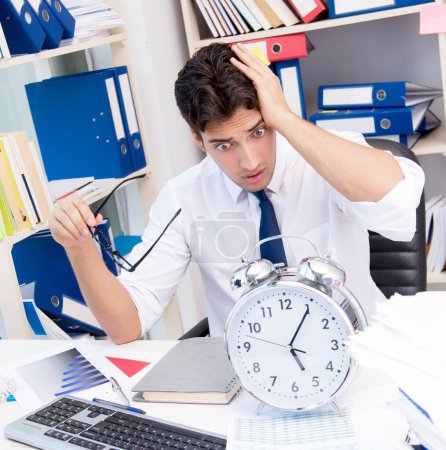 Photo for Businessman working in the office with piles of books and papers doing paperwork - Royalty Free Image