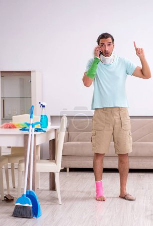 Photo for The young injured man cleaning the house - Royalty Free Image