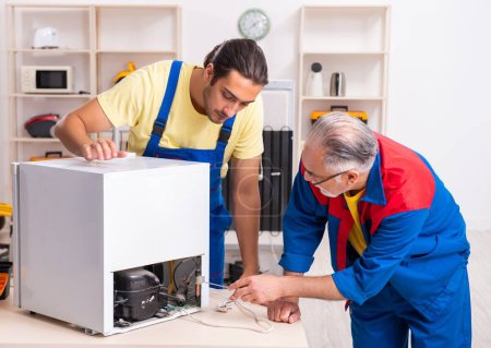 Photo for The two contractors repairing fridge at workshop - Royalty Free Image