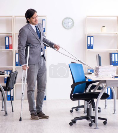 Photo for The leg injured male employee working in the office - Royalty Free Image
