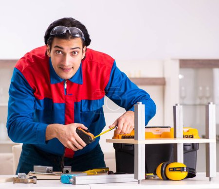 Téléchargez les photos : Le jeune entrepreneur réparer des meubles à la maison - en image libre de droit