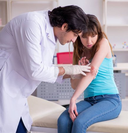 die junge am Arm verletzte Frau besucht jungen Arzt Traumatologen
