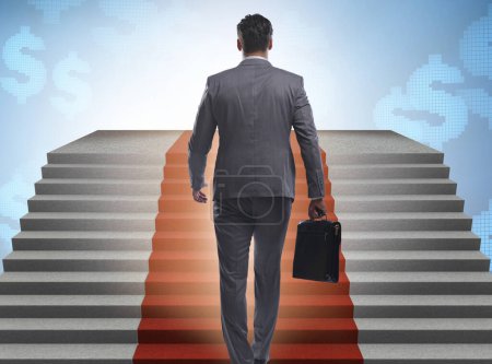 Téléchargez les photos : Le jeune homme d'affaires monte les escaliers et le tapis rouge - en image libre de droit