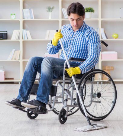 Téléchargez les photos : L'homme handicapé en fauteuil roulant nettoyage maison - en image libre de droit