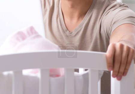 Téléchargez les photos : Le jeune papa étudiant se prépare pour les examens et s'occupe du bébé - en image libre de droit