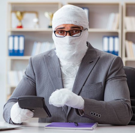 Téléchargez les photos : Homme d'affaires bandé travaillant dans le bureau faisant de la paperasserie - en image libre de droit