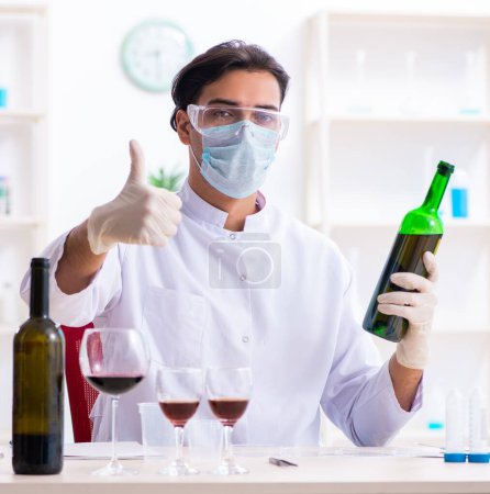 El químico masculino examinando muestras de vino en el laboratorio