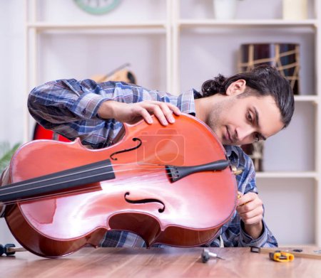 The young handsome repairman repairing cello
