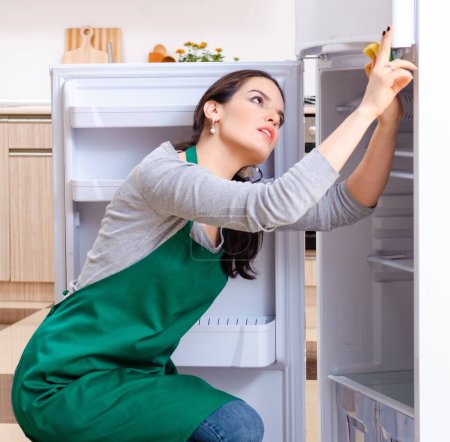 Photo for The young woman cleaning fridge in hygiene concept - Royalty Free Image