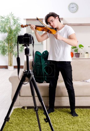 Photo for The young male blogger playing violin at home - Royalty Free Image