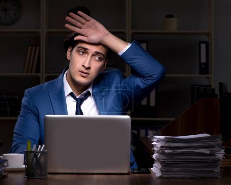 Téléchargez les photos : Le jeune employé de sexe masculin qui travaille la nuit au bureau - en image libre de droit