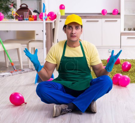 Le jeune entrepreneur masculin faisant des travaux ménagers après la fête