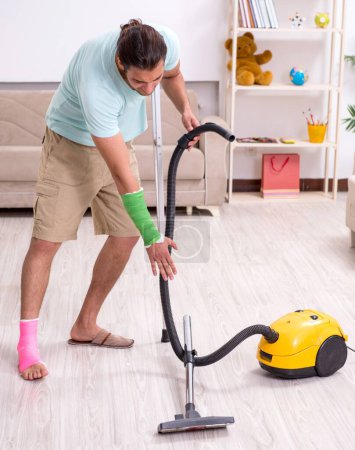 Photo for The young injured man cleaning the house - Royalty Free Image