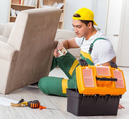 Téléchargez les photos : Le travailleur répare les meubles à la maison - en image libre de droit