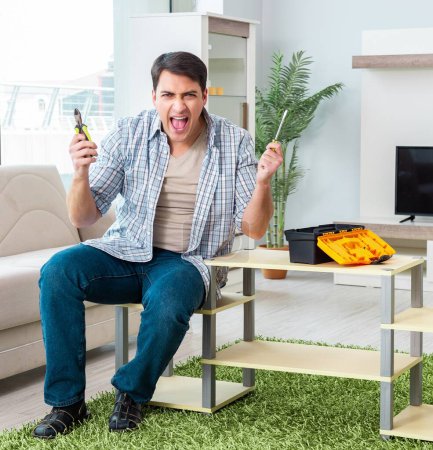 Téléchargez les photos : L'homme assemblant des meubles à la maison - en image libre de droit