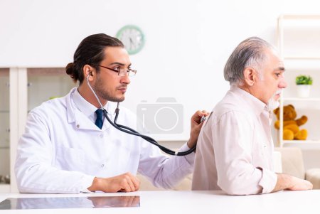 Téléchargez les photos : Le jeune médecin de sexe masculin rend visite à un vieux patient à la maison - en image libre de droit