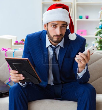 Téléchargez les photos : L'homme d'affaires travaillant à la maison pendant Noël - en image libre de droit
