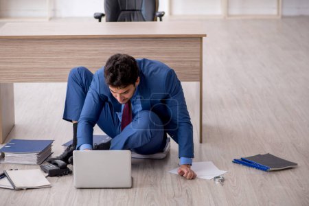Photo for Young employee unhappy with excessive work at workplace - Royalty Free Image