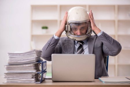 Young businessman employee wearing spacesuit at workplace
