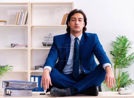 Téléchargez les photos : Le jeune homme d'affaires assis et travaillant dans le bureau - en image libre de droit