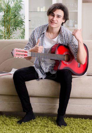 Foto de El joven con la guitarra en casa - Imagen libre de derechos