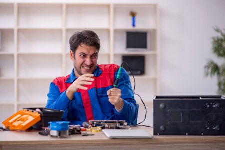 Junger Reparateur repariert Computer in Werkstatt