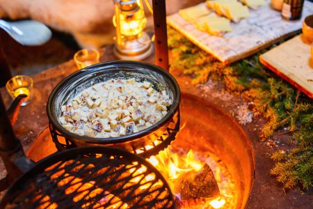 Téléchargez les photos : Délicieux fromage cuit au four appâté cuit sur feu ouvert dans une cabane appât - en image libre de droit