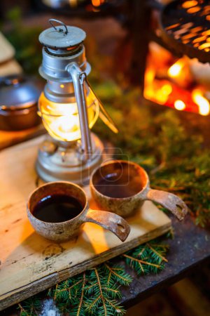 Photo for Lappish glogg mulled wine drink served in wooden cups in lappish hut next to open fire - Royalty Free Image