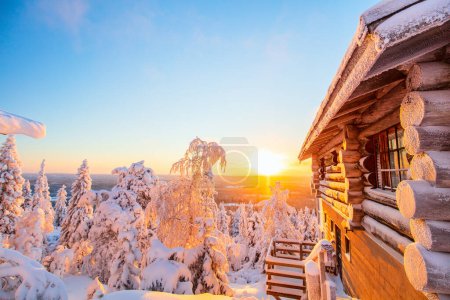 Téléchargez les photos : Beau paysage hivernal avec cabane en bois et arbres enneigés au coucher du soleil en Laponie Finlande - en image libre de droit