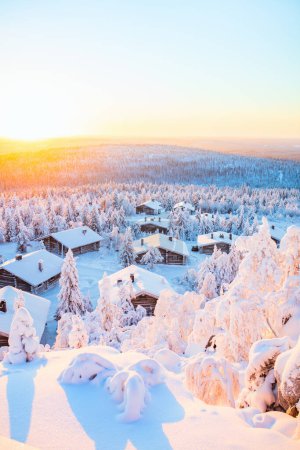 Téléchargez les photos : Superbe vue coucher de soleil sur des cabanes en bois et des arbres enneigés en Laponie finlandaise - en image libre de droit